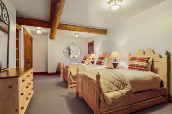 A bedroom with two beds, a large mirror, and a wooden dresser.
