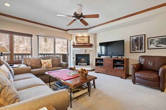 The inviting living area of St James Place 335 features a cozy fireplace, comfortable seating, and large windows offering scenic winter views.