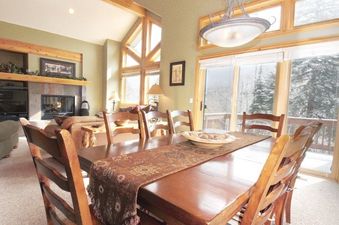 A spacious dining area with a long wooden table and chairs, offering views of a snowy outdoor landscape through large windows.