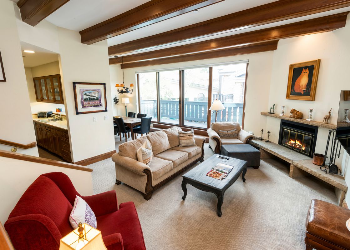 The inviting lounge area features a fireplace, a comfortable sofa, and large windows offering a glimpse of the outdoors.