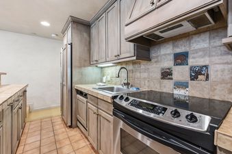 A rustic-style kitchen at Stonebridge at Village Center with wooden cabinets, tile countertops, and stainless steel appliances.