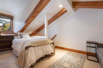 A cozy guest bedroom at Villa Valhalla 9 with a single bed, a wooden dresser, and a window overlooking a scenic autumn landscape.