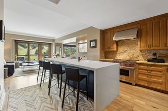 A modern kitchen with stainless steel appliances and a breakfast bar overlooking a mountain view