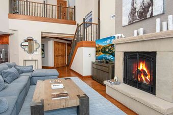 The living room of Ritz Carlton Vail 402 features a large sectional sofa, a coffee table, a fireplace, a large flat-screen TV, and a view of the ski slopes.
