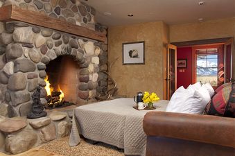 The Grand Teton Vista's cozy bedroom with a stone fireplace offers a warm and inviting atmosphere.