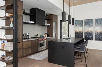 The modern kitchen at Moonlight Basin 5 Thistle Way features dark wood cabinets, stainless steel appliances, and a large island with bar seating.