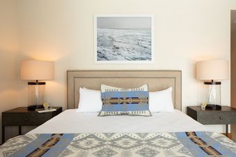 A cozy and elegantly styled king bed with Southwestern patterned pillows and matching throw at Granite Ridge Lodge 17.