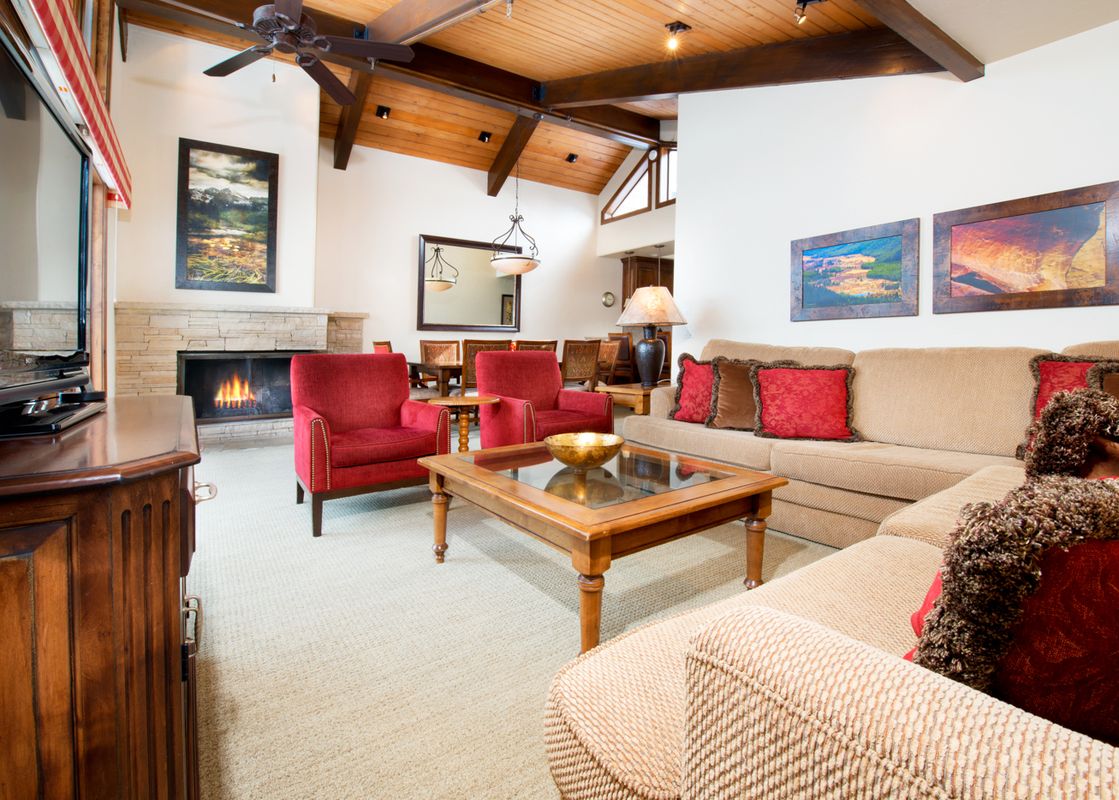 A cozy living room in The Gant Aspen 4 Bedroom Premier with a fireplace, comfortable seating, and rustic wooden accents.