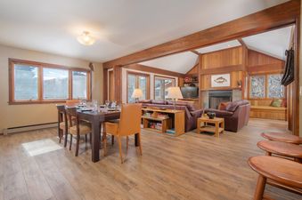Open-plan dining and living area of Teewinot D4 with large windows, wood accents, and a cozy fireplace.