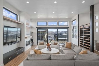 A living room with a sectional couch and a fireplace, overlooking a mountain view.