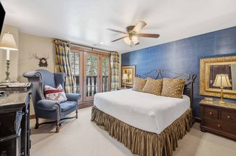 A cozy bedroom with a king-sized bed, blue accent wall, and French doors leading to an outdoor space.
