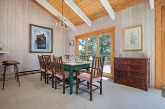 Fisher House dining room featuring a wooden table with rustic log chairs under a vaulted ceiling.