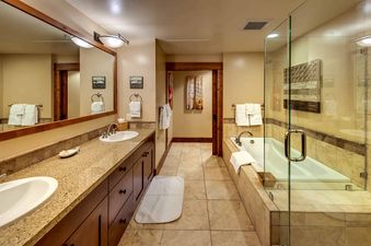 A modern bathroom with a double vanity, a soaking tub, and large tile floors.
