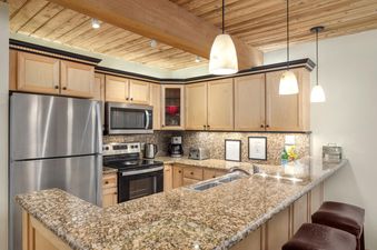 A kitchen at Trails 103 featuring granite countertops, wood cabinets, and stainless steel appliances.