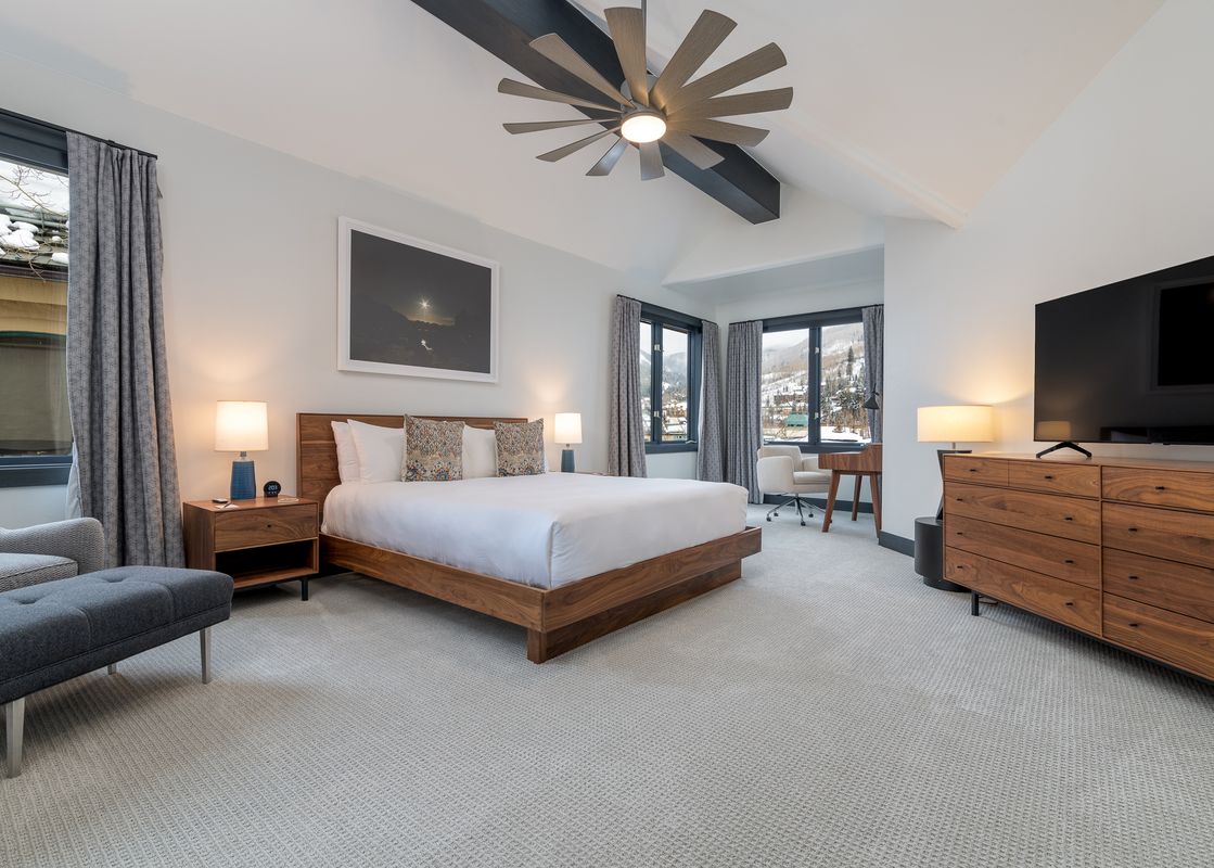 The beautiful bedroom in Stone Creek Chalet at The Aspens features a king bed, wooden furniture, and large windows.