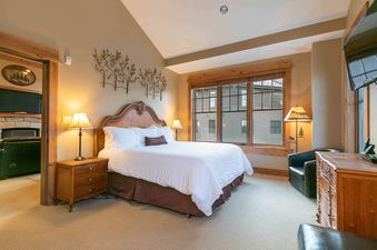 A bedroom with a large bed, two nightstands, a dresser, and a television.