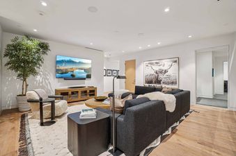 A modern and luxurious living room at Founders Place 1701 featuring a large wall-mounted TV, a sectional sofa, a coffee table, and stylish decor, with a large potted plant adding a natural element.