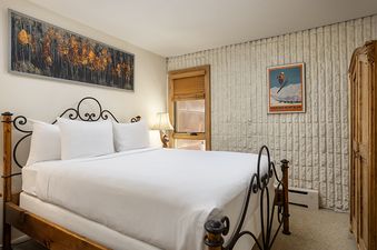 A cozy bedroom in Vail 21 406 with a large bed, rustic wooden furniture, and a nature-inspired art piece above the headboard.