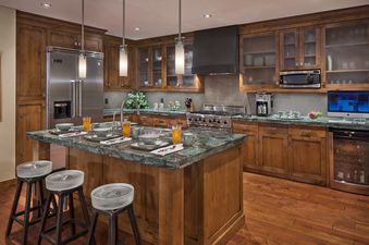 The kitchen in Flat Tops Peak Penthouse One Steamboat Place 701 features a spacious island with a marble countertop, modern appliances, and wooden cabinetry.