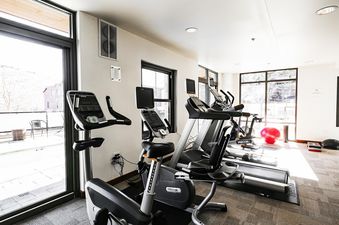 A bright and modern fitness center at Lowell 201A with various exercise machines, large windows, and fitness accessories.