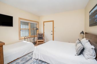 A cozy bedroom in Sundance Condos 202 featuring a large bed with a wooden headboard, decorative pillows, a single bed, a floor lamp, and a patterned rug.