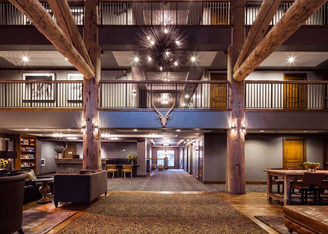 The multi-level grand lobby of Teton Mountain Lodge and Spa Lodge King featuring wooden pillars and a starburst chandelier.
