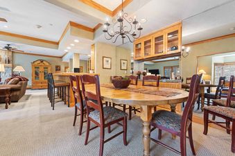 A large, oval wooden dining table with patterned chairs, illuminated by an iron chandelier, creates an inviting dining area.