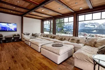 A spacious living room with a large sectional sofa, perfect for lounging and enjoying the stunning mountain views from the large windows.
