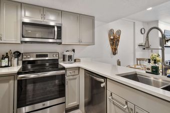 A modern kitchen with stainless steel appliances, a double-basin sink, and white countertops.