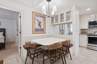 A cozy dining nook with a white table, booth seating, and three wooden chairs in The Charter C250.
