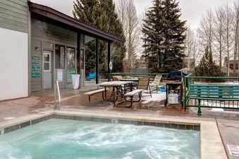 Outdoor hot tub and patio area with seating and a grill at Sundance Jackson Hole.
