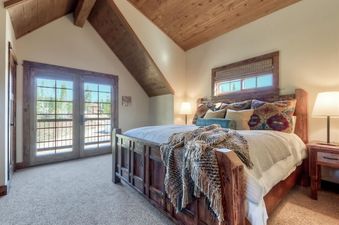 A cozy bedroom with a large wooden bed, two bedside lamps, and French doors leading to an outdoor space.