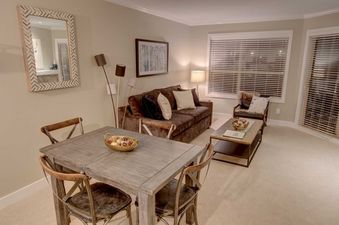 The living area features a brown couch, coffee table, and a dining table with chairs.