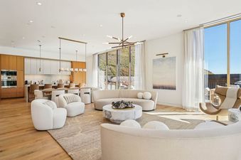 An expansive open-concept living room and dining area at Founders Place 1704, featuring contemporary furniture, large windows with mountain views, and a modern kitchen.