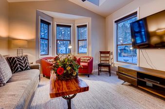 A cozy living room at High Street Retreat, featuring comfortable seating, a television, and a view of the snowy outdoors.