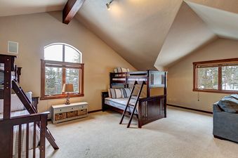 A bedroom with a bunk bed, a couch, and a window looking out onto a snowy forest.