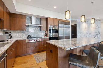 The Lion W605 kitchen featuring wooden cabinetry, stainless steel appliances, and granite countertops.
