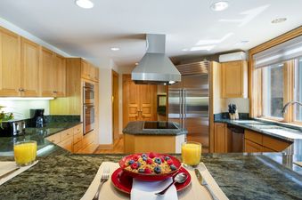 Well-equipped kitchen at 411 Beaver Creek Lodge with light wood cabinets, granite countertops, and breakfast set on the counter.