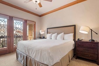 A serene bedroom at The Charter F3205 with a king-sized bed, two nightstands with lamps, and large windows offering an exterior view.