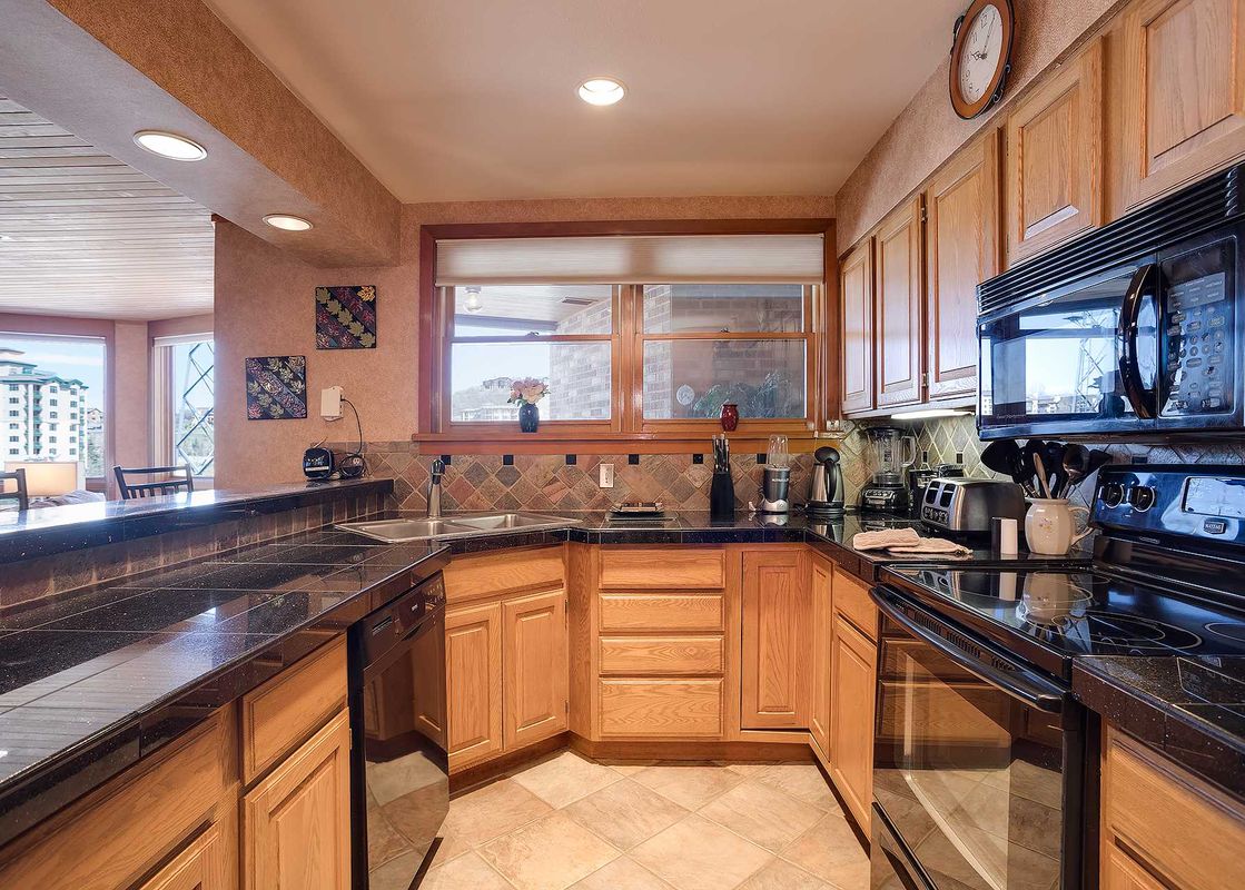 A well-appointed kitchen in Chateau Chamonix CX133 with black granite countertops, wood cabinets, and modern appliances.