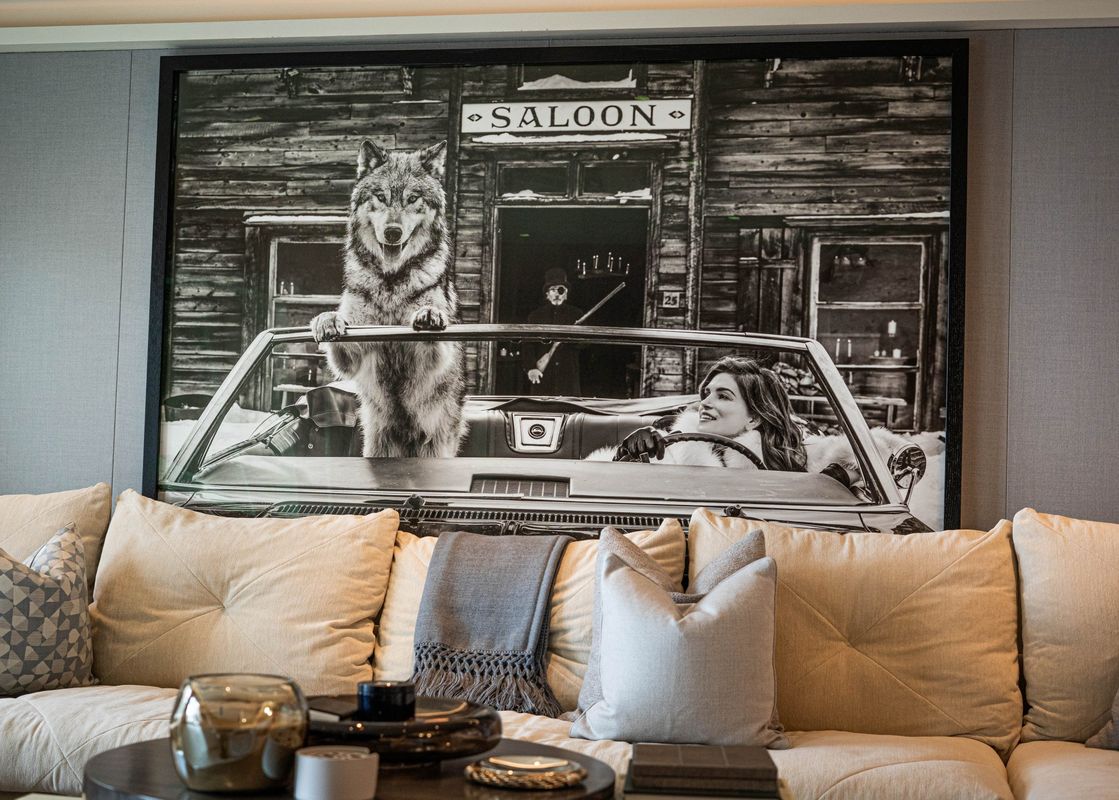 The Clubhouse living room features a couch with pillows and a throw blanket, in front of a large framed black and white photograph.