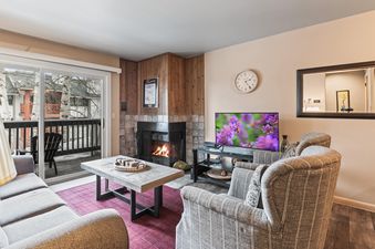 A cozy living room at Snow Flower 107 Park City with a fireplace, TV, and balcony access.