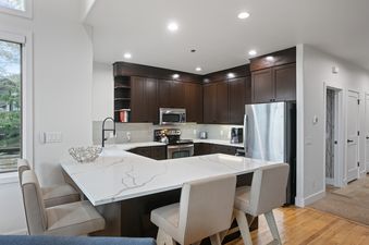 A modern kitchen in Twin Pines 5 with dark cabinetry and a white quartz island.