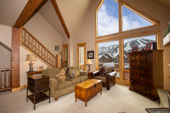 A spacious and inviting living room at Antlers at Lakota 406 with a comfortable sofa, armchair, and stunning mountain views through large windows.