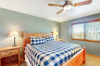 A cozy bedroom at Big Moose Lodge features a wooden bed frame and blue and white checkered bedding.