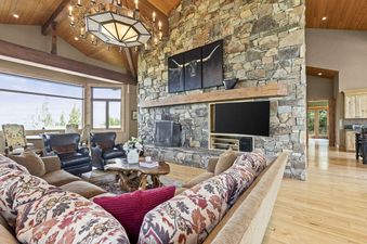 A large living room with a stone fireplace, a flat-screen TV, and a sectional sofa.