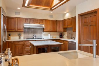 A spacious kitchen with rich wood cabinetry, stainless steel appliances, granite countertops, and a central island.