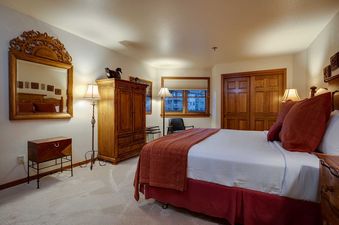 A master bedroom at Chateau Chamonix CX123 with a bed, wooden furniture, and a window.