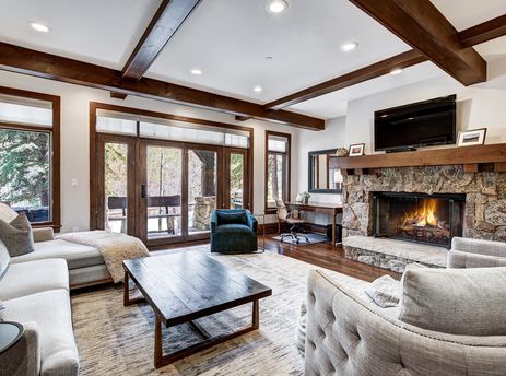 A cozy living room in Snow Cloud Lodge 515 features a stone fireplace, large television, comfortable sofas, and expansive windows offering scenic views.