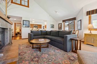 A cozy living area in Kiva 428, showcasing a plush gray sectional sofa, a coffee table, and a fireplace with a tile surround.
